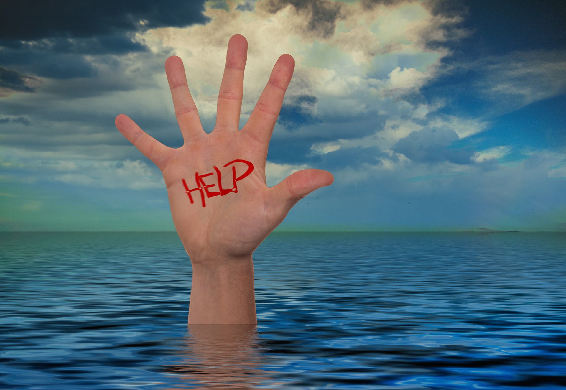 Hand with word "Help" written in red ink sticking out of the water